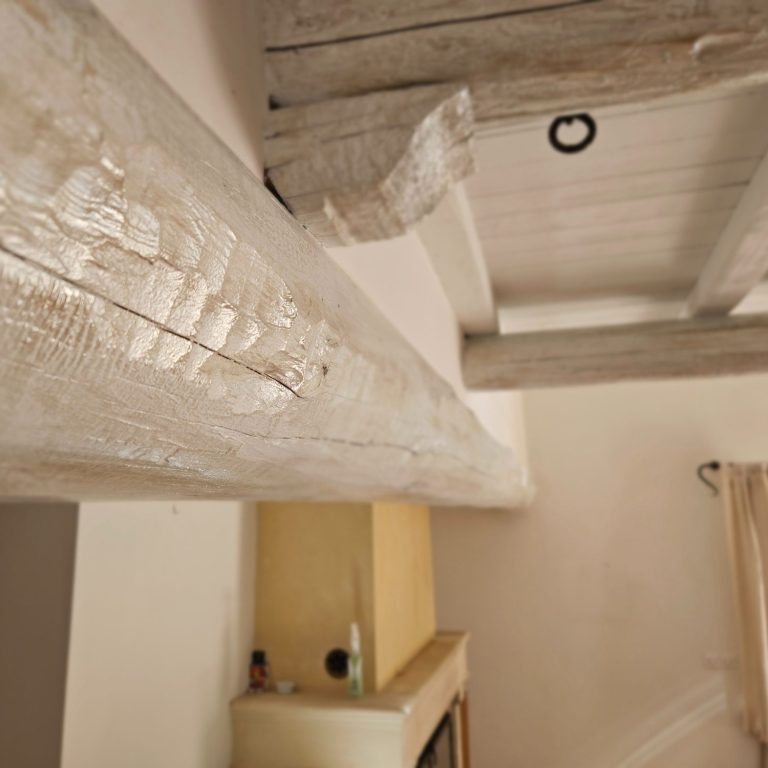 Plafond avec poutres en bois blanchi et murs clairs dans un intérieur chaleureux.