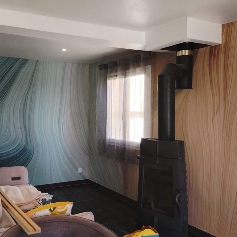 Salon moderne avec un mur aux motifs ondulés et un poêle noir. Canapé confortable en face.