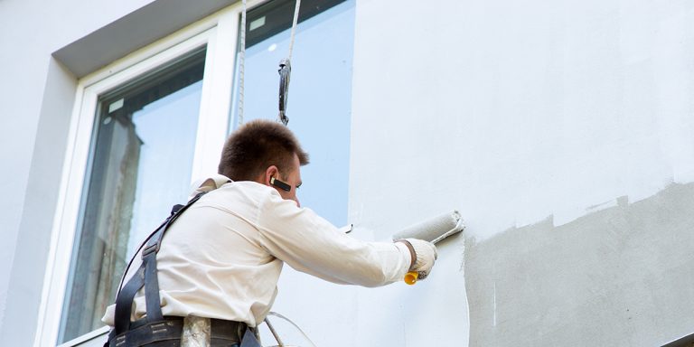 Homme en train de peindre un mur avec un rouleau à peinture.