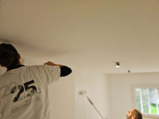Travailleurs peignant un plafond dans une pièce lumineuse.