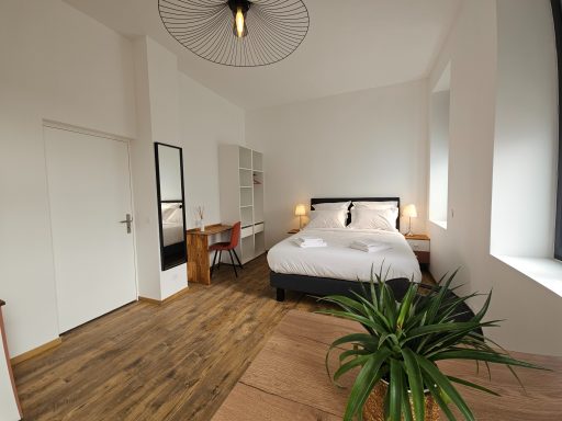 Chambre lumineuse avec un lit, un bureau et des plantes dans un décor moderne.