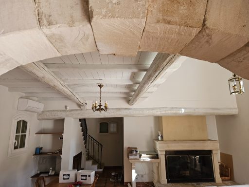 Intérieur lumineux avec poutres apparentes, cheminée et mezzanine visible.